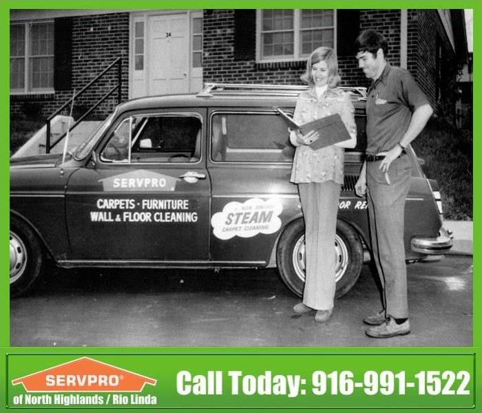 Vintage image of employee describing things to customer in front of vehicle 